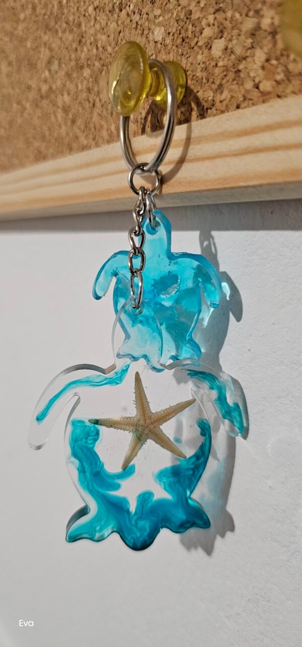 20250404_120520 Llavero de Tortuga, de color transparente y color azul con una estrella de mar en su interior acompañado de una pequeña tortuga en tono azul claro.