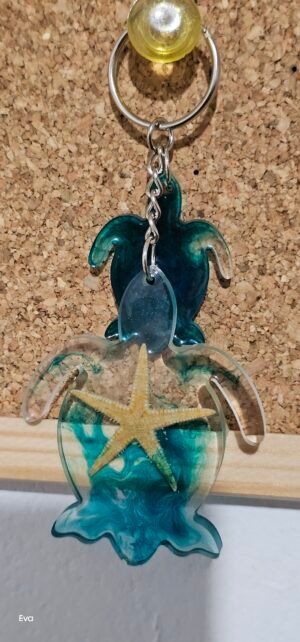 Llavero de Tortuga, de color transparente y azul con una estrella de mar en su interior acompañado de una pequeña tortuga en tono azul oscuro.